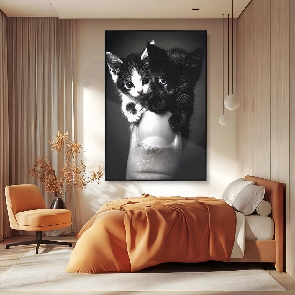 Tablou canvas cu tablou canvas cu doi pisoi mici agatati de un deget, in rama de aluminiu negru, pe perete intr-un dormitor